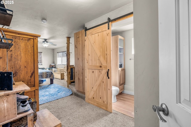 hall featuring a barn door, baseboards, and carpet