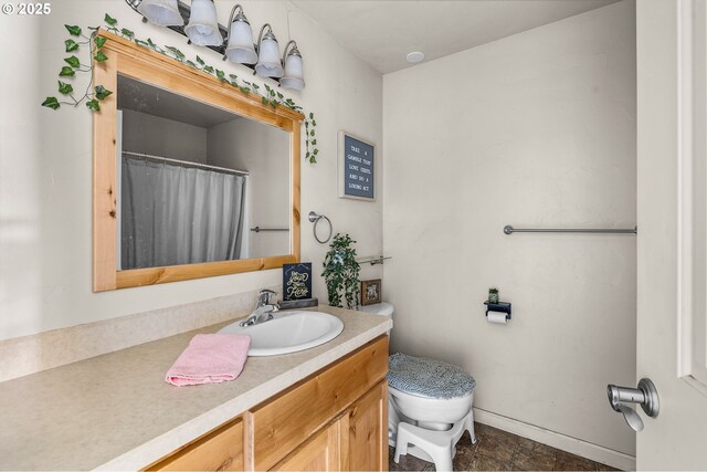 bathroom with baseboards, toilet, and vanity