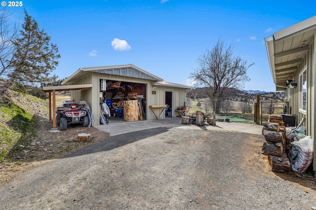 exterior space with an outdoor structure, fence, and dirt driveway