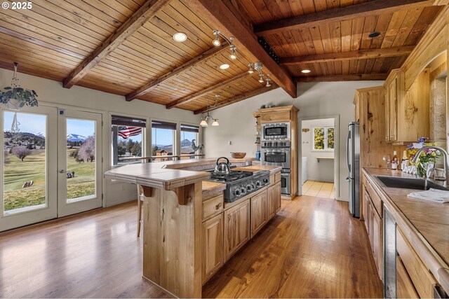 kitchen featuring light wood-type flooring, a sink, a center island, appliances with stainless steel finishes, and wood ceiling