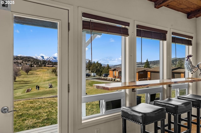 interior space featuring beamed ceiling, plenty of natural light, and a mountain view