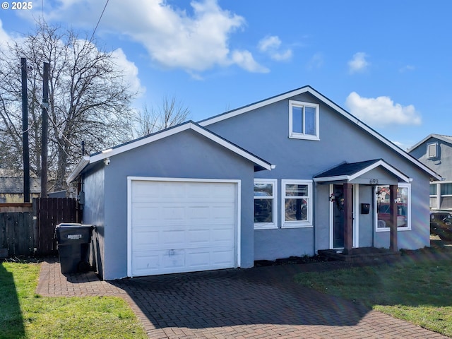 view of front facade featuring an attached garage, fence, decorative driveway, and stucco siding