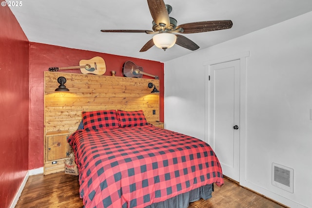 bedroom with baseboards, ceiling fan, visible vents, and wood finished floors