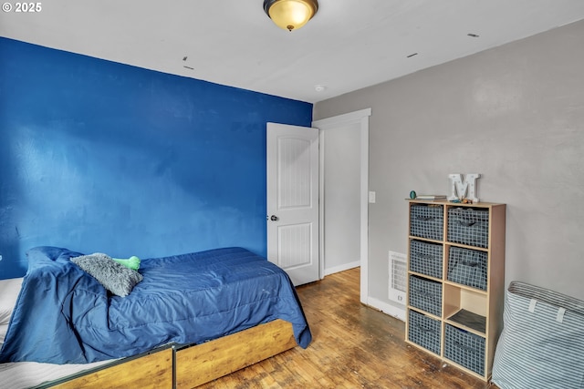 bedroom with wood finished floors, visible vents, and baseboards