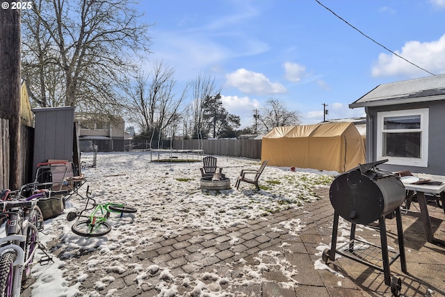 view of yard with an outdoor fire pit, a trampoline, a patio area, and a fenced backyard