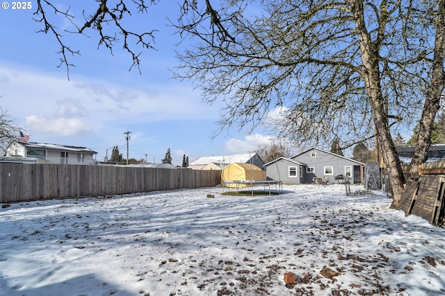 snowy yard featuring a fenced backyard and a trampoline