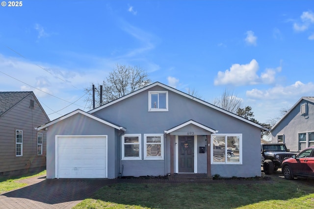 bungalow-style house with a garage, decorative driveway, a front yard, and stucco siding