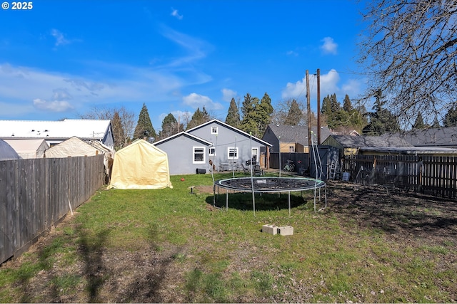 view of yard featuring a fenced backyard, a trampoline, and an outbuilding