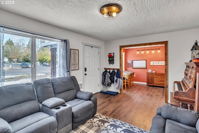 living room featuring a textured ceiling, baseboards, and wood finished floors