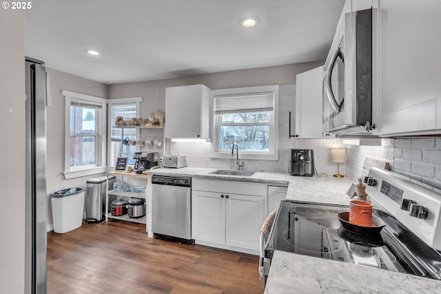 kitchen featuring appliances with stainless steel finishes, dark wood-type flooring, a sink, and white cabinetry