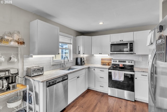 kitchen featuring appliances with stainless steel finishes, white cabinetry, and a sink