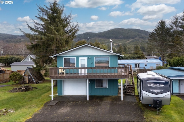 view of front of house featuring a deck with mountain view, driveway, a front lawn, stairway, and a garage