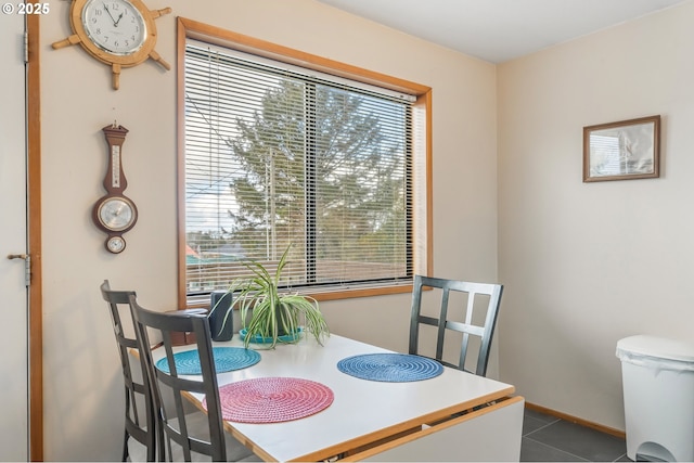 dining area featuring dark tile patterned floors and baseboards