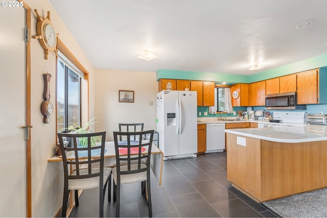 kitchen featuring a wealth of natural light, white appliances, a peninsula, and light countertops