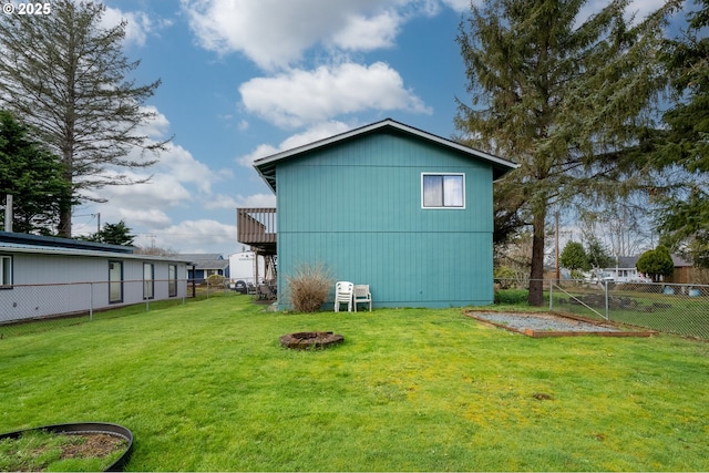 back of house with a garden, a yard, fence, and an outdoor fire pit