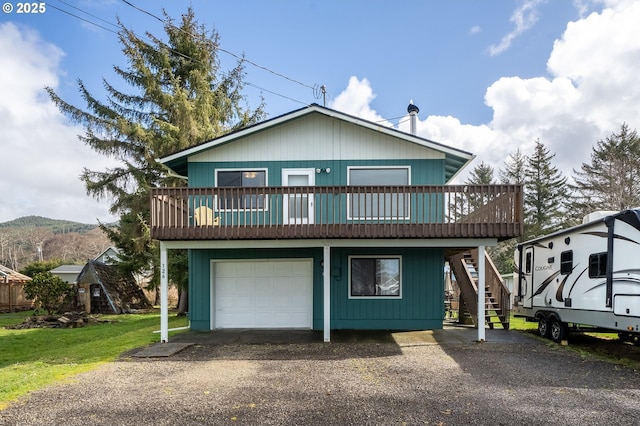 view of front of home featuring driveway, a front yard, an attached garage, a wooden deck, and stairs