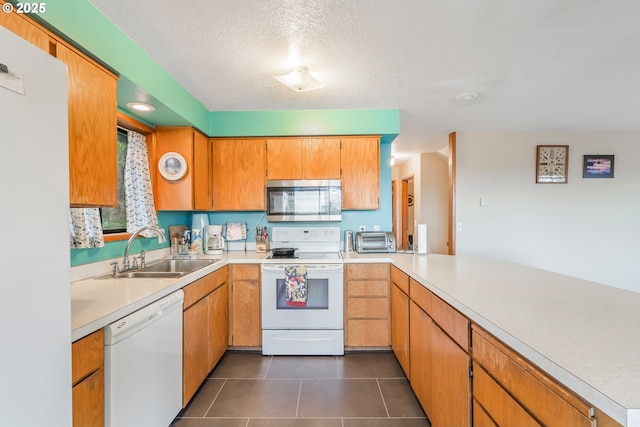 kitchen featuring white appliances, dark tile patterned floors, light countertops, and a sink