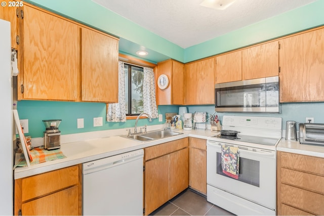 kitchen with white appliances, dark tile patterned floors, light countertops, and a sink