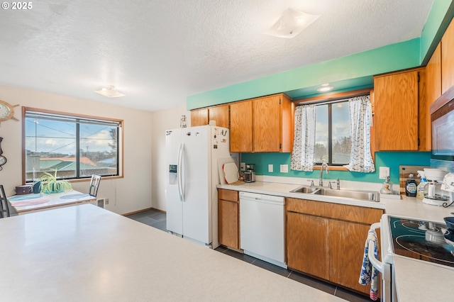 kitchen featuring white appliances, a textured ceiling, light countertops, and a sink