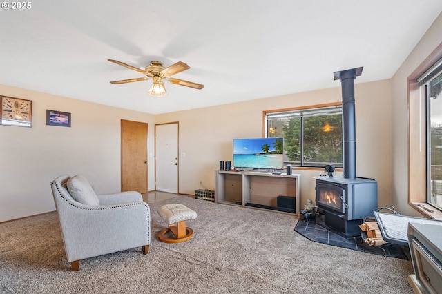 carpeted living area featuring ceiling fan and a wood stove