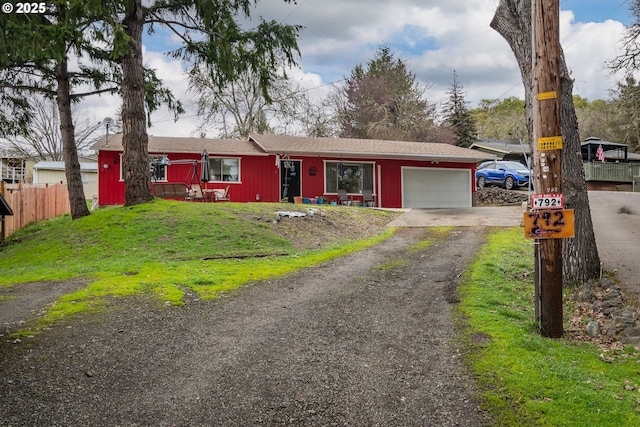 ranch-style home featuring a front yard, driveway, an attached garage, and fence