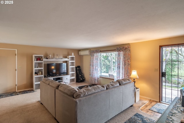 living area with a healthy amount of sunlight, light carpet, baseboards, and a wall mounted AC