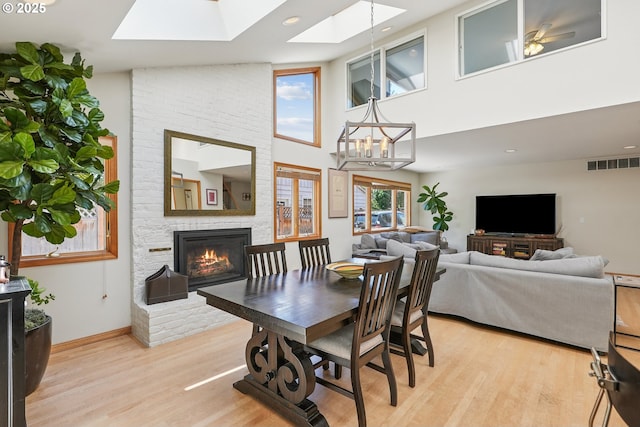 8895 SW Bohmann Pkwy, Portland, OR 97223 - dining area featuring a skylight, a large fireplace, light wood-style flooring, a towering ceiling, and baseboards