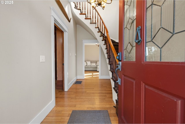 entrance foyer with an inviting chandelier, a towering ceiling, and light hardwood / wood-style floors