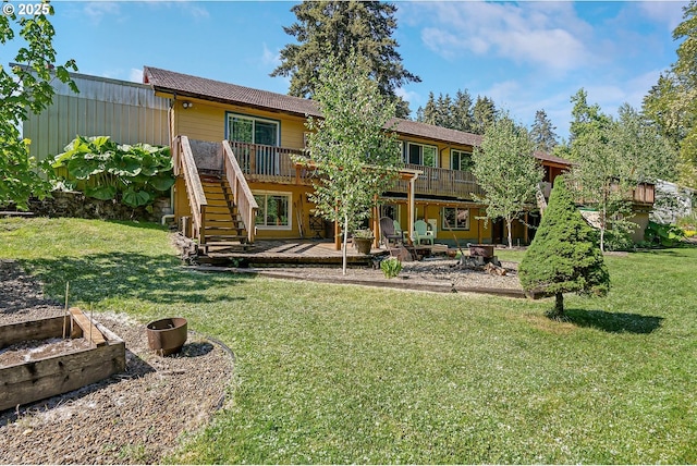 rear view of property featuring a garden, a deck, stairway, a lawn, and a patio area