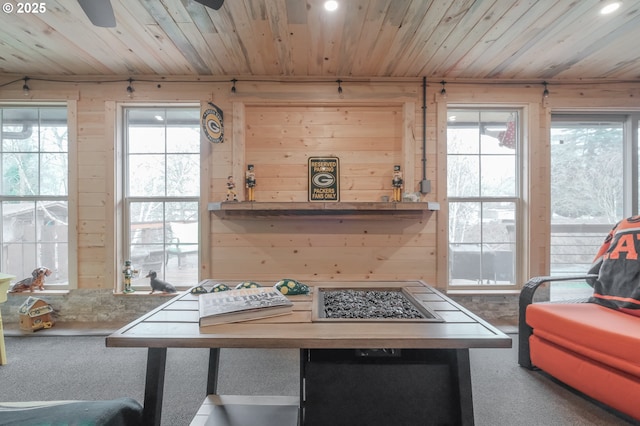 dining space featuring wood ceiling, carpet flooring, wooden walls, and ceiling fan