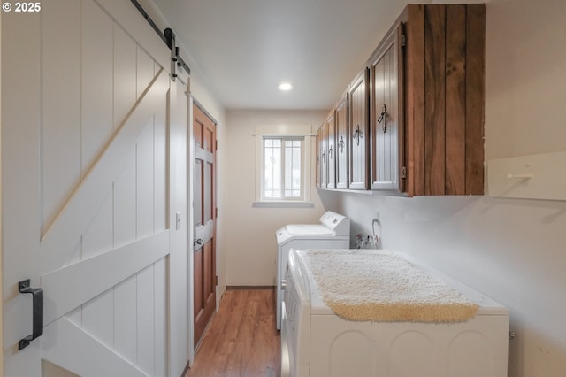 laundry area with washing machine and clothes dryer, cabinet space, light wood-style flooring, recessed lighting, and a barn door