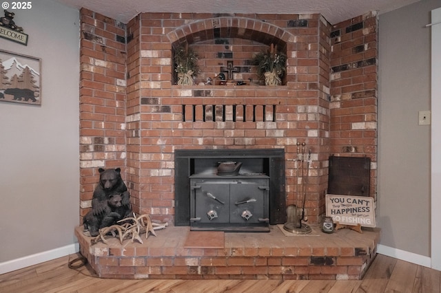 detailed view of wood finished floors, baseboards, and a fireplace