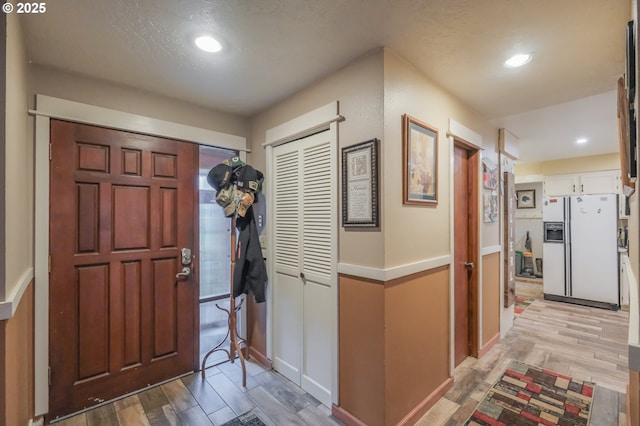 foyer with light wood-style floors, recessed lighting, baseboards, and a textured ceiling