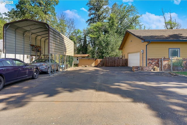 view of side of home with driveway, a carport, fence, a garage, and brick siding