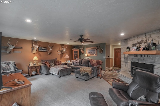 living room featuring ceiling fan, a textured ceiling, carpet flooring, a fireplace, and recessed lighting