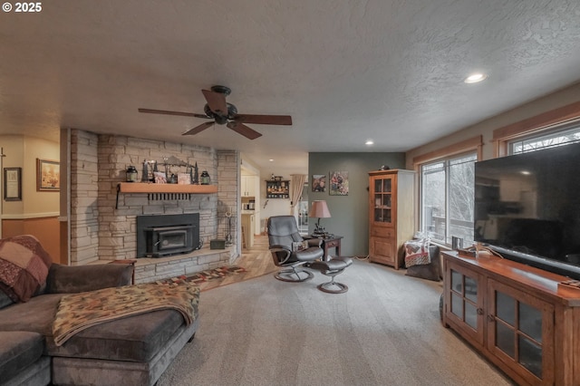 carpeted living room with ceiling fan, a textured ceiling, recessed lighting, and a wood stove