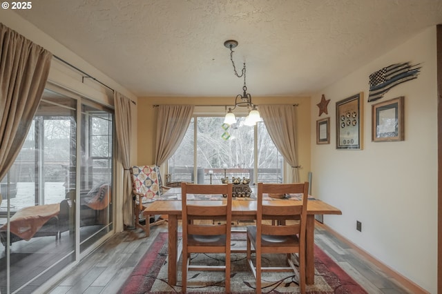 dining room with wood finished floors, a textured ceiling, and a chandelier