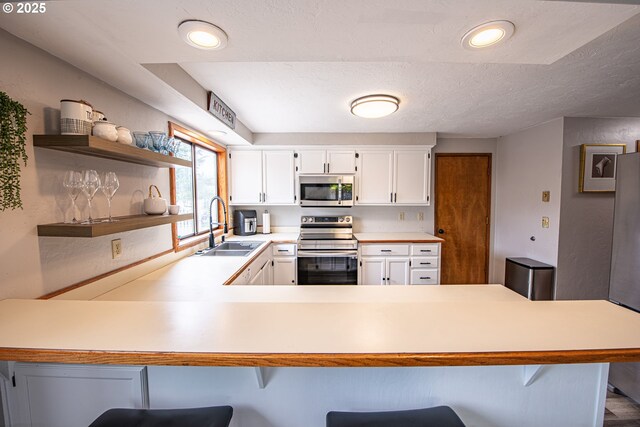 3308 Honeywood St, Eugene, OR 97408 - kitchen with stainless steel appliances, a sink, a peninsula, light countertops, and a breakfast bar