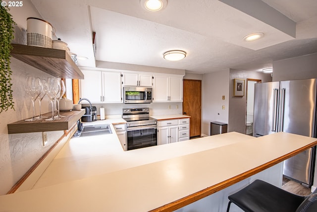 3308 Honeywood St, Eugene, OR 97408 - kitchen with stainless steel appliances, a sink, a peninsula, light countertops, and white cabinets