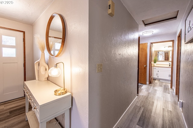 3308 Honeywood St, Eugene, OR 97408 - corridor with light wood finished floors, a textured wall, a textured ceiling, baseboards, and attic access