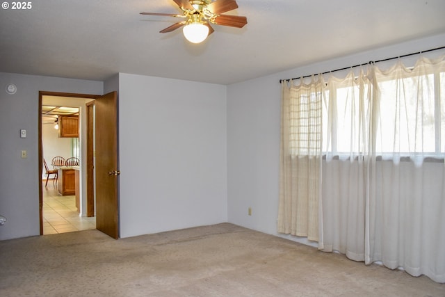 spare room featuring light carpet, ceiling fan, and light tile patterned floors