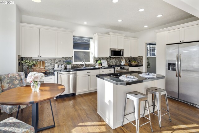 kitchen featuring a breakfast bar, white cabinetry, sink, a center island, and stainless steel appliances