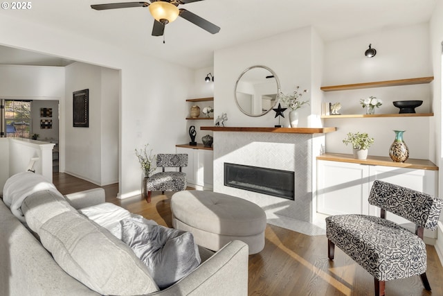 living room featuring ceiling fan, dark hardwood / wood-style floors, and a tile fireplace