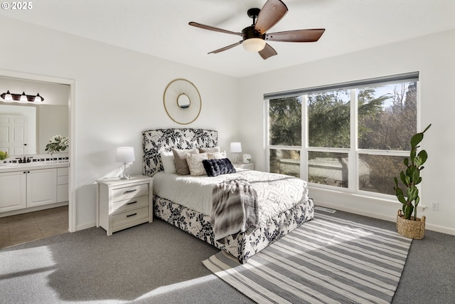 bedroom featuring ceiling fan, ensuite bathroom, and dark colored carpet