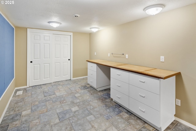 unfurnished office featuring built in desk and a textured ceiling