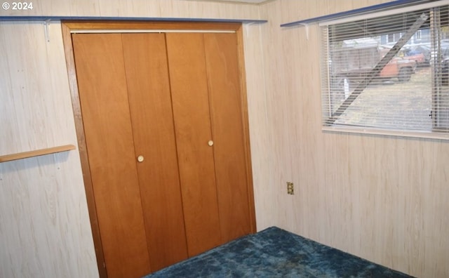 unfurnished bedroom featuring a closet and wood walls