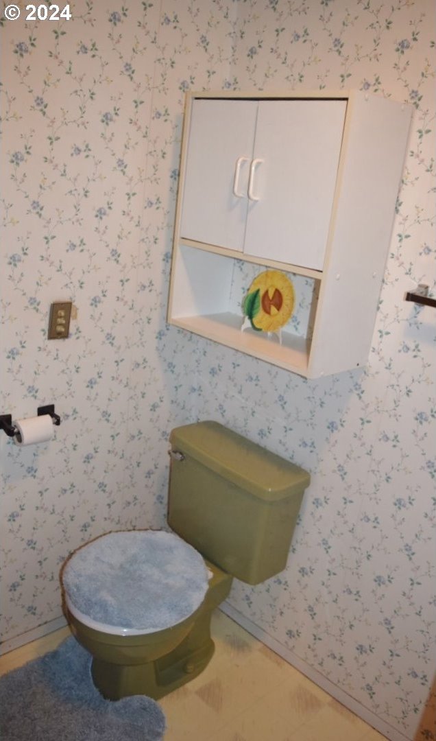 bathroom with toilet and wallpapered walls