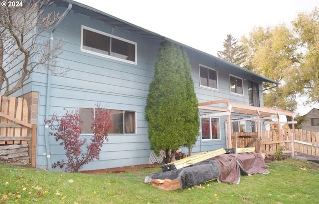 rear view of property with fence and a yard
