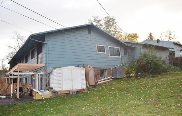 rear view of house featuring a storage shed, an outbuilding, a lawn, and central AC