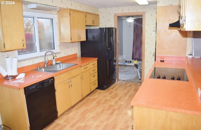kitchen featuring light wood-type flooring, a sink, light countertops, black appliances, and wallpapered walls